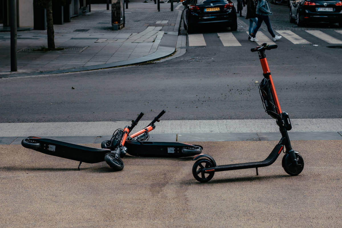 2 scooters lying on the floor after an accident another scooter standing next to them.