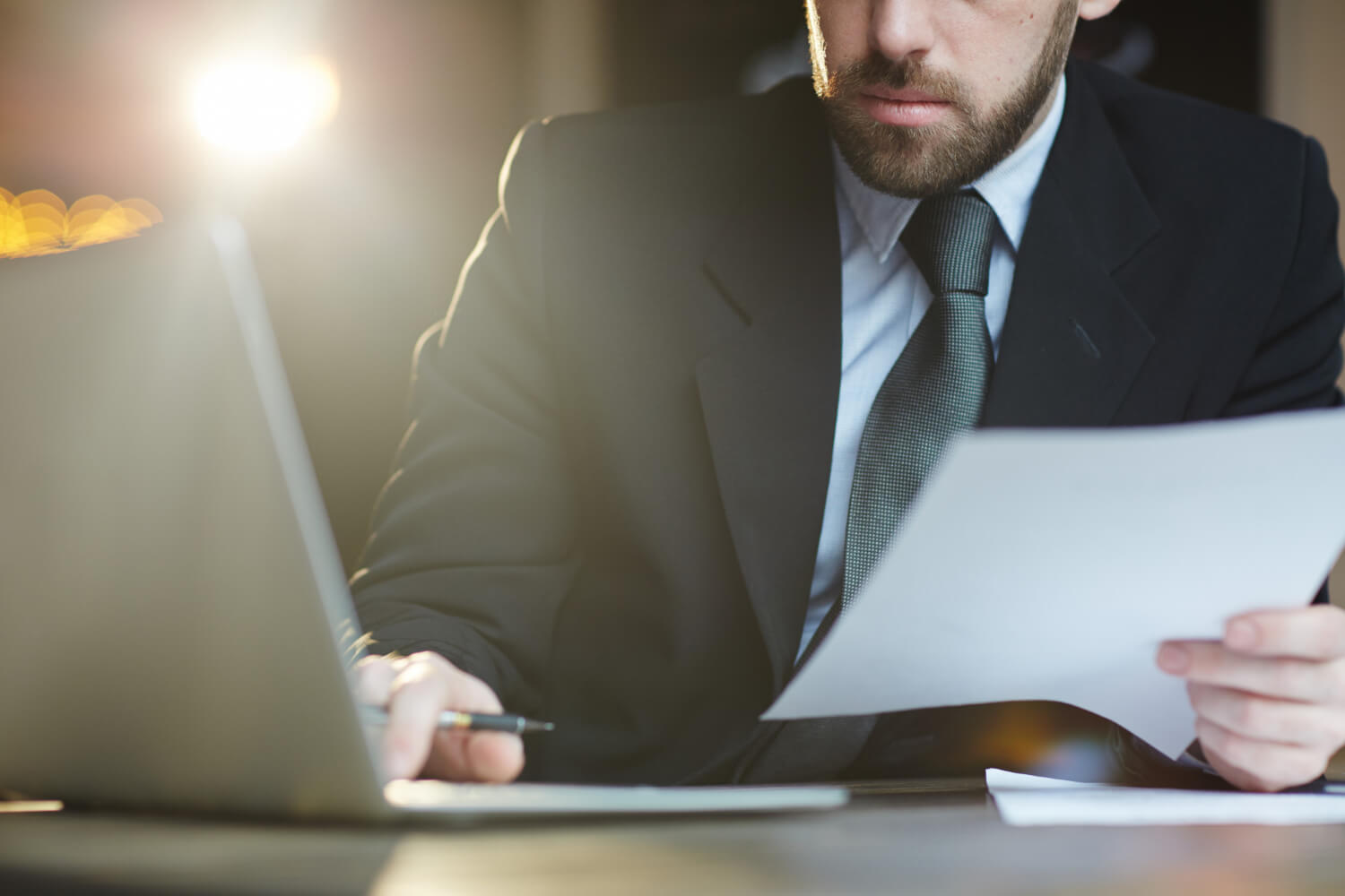 Bearded man in a suit going over important documents.