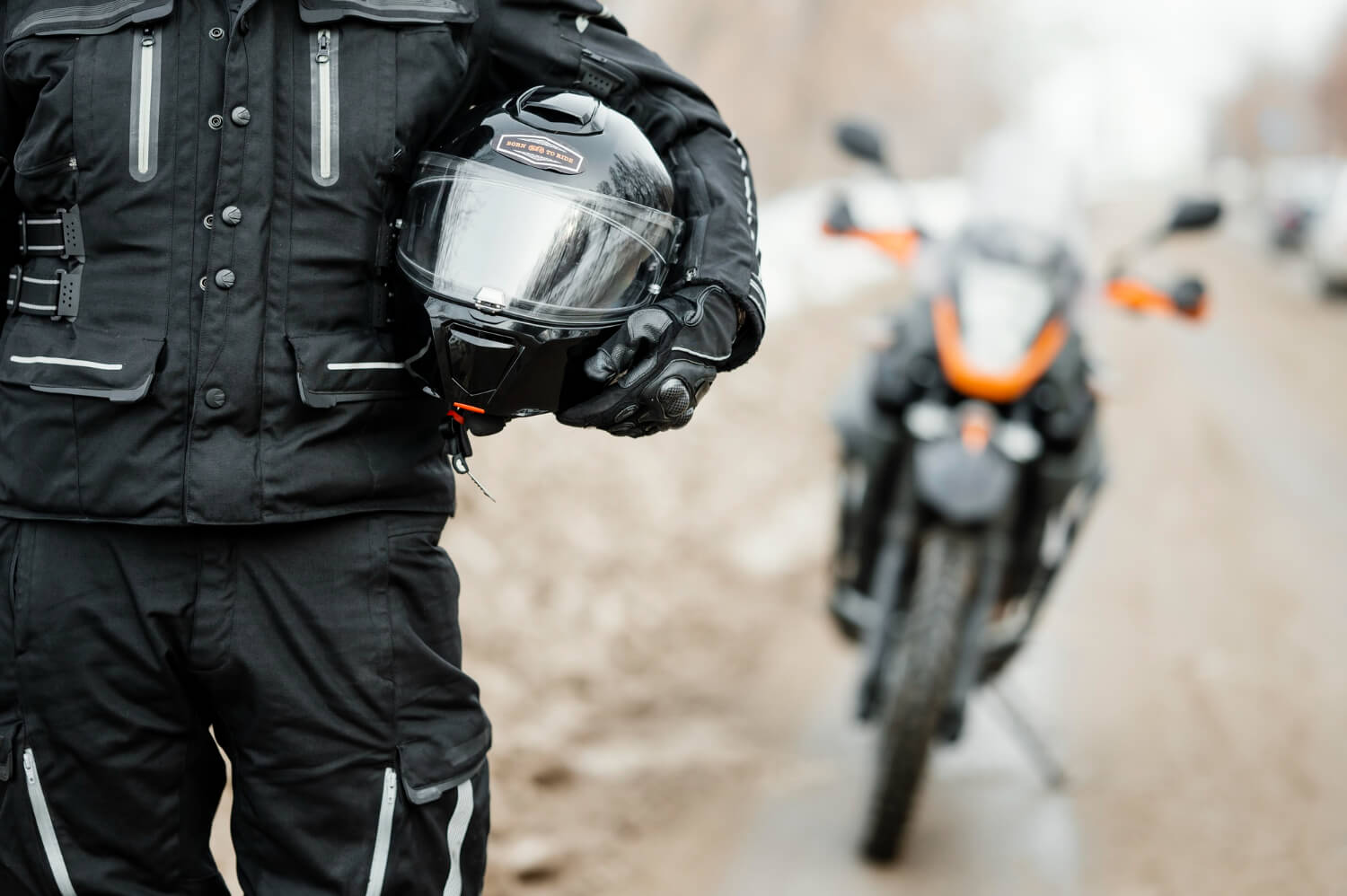Retrato de hombre con casco de motociclista y equipo de seguridad completo con motocicleta a la espalda. 