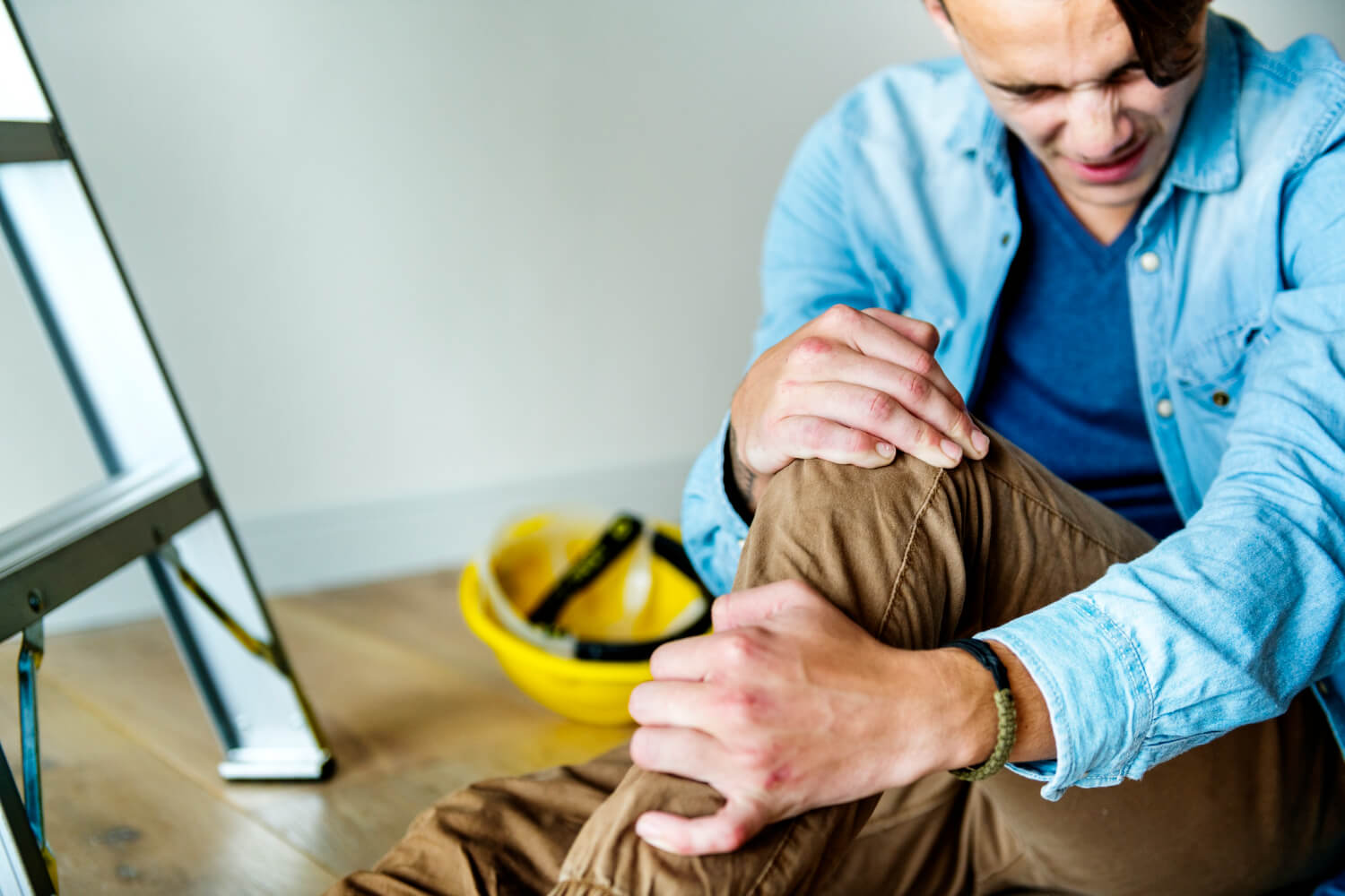 Male construction worker holding his knee in pain.