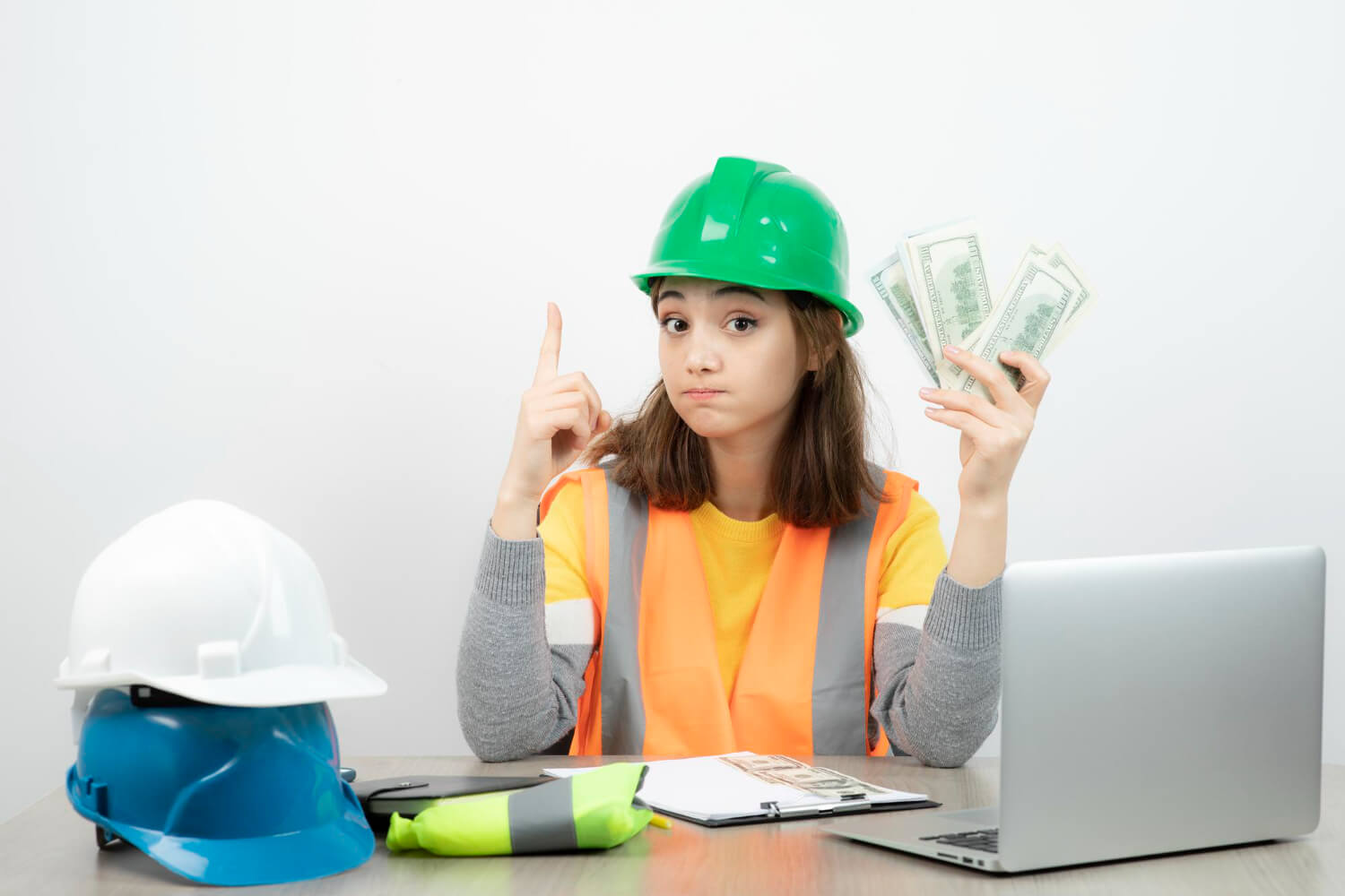 Female construction worker holding a wad of cash. 