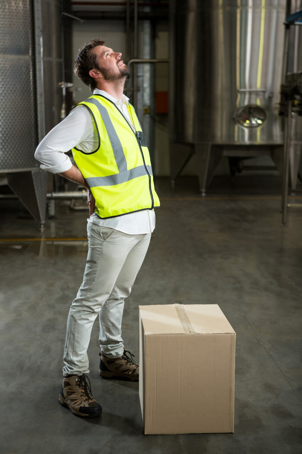 Male warehouse worker holding his back in pain.