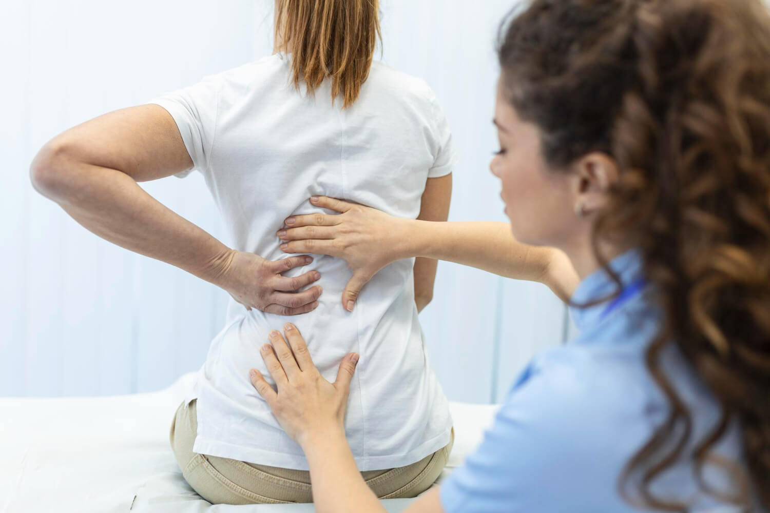 Profesional médico tratando el dolor de espalda de una mujer.
