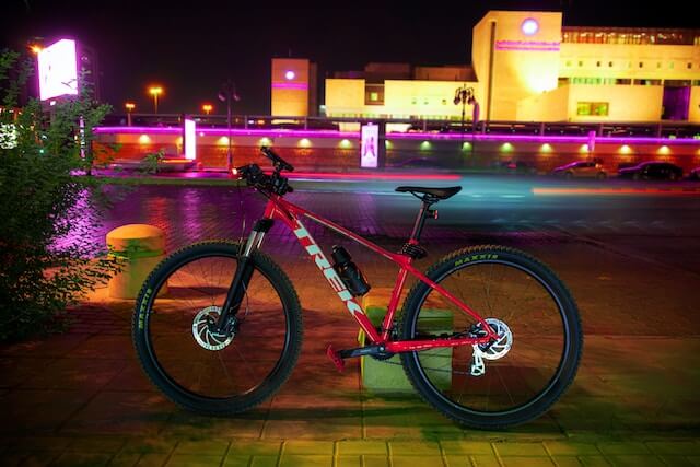 Bicicleta apoyada en un pequeño poste por la noche. 