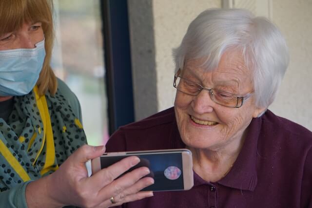 Anciana disfrutando y viendo un vídeo de una enfermera  