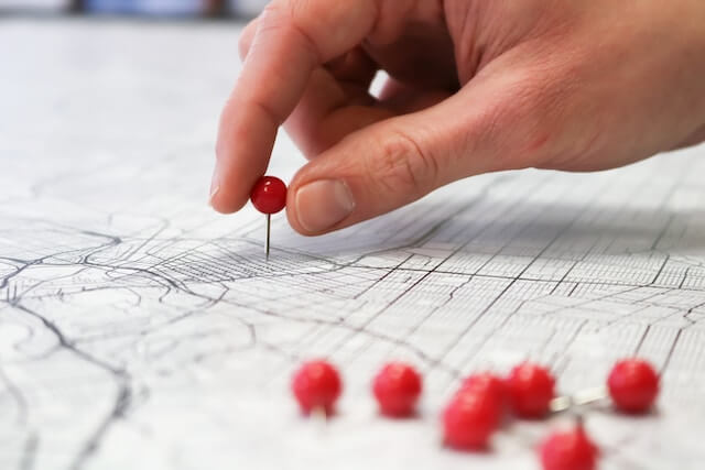 Hombre colocando chinchetas en un mapa de papel 