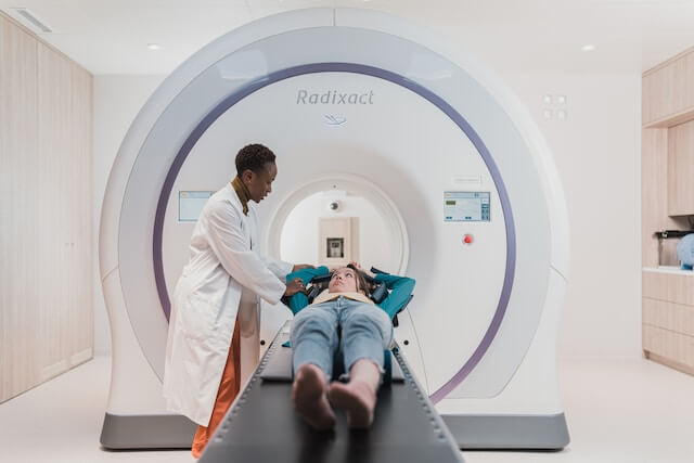 Hombre colocando a una paciente en la máquina de resonancia magnética. 