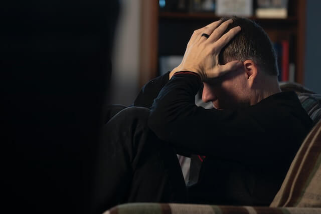 Hombre frustrado en un sofá sujetándose la cabeza. 