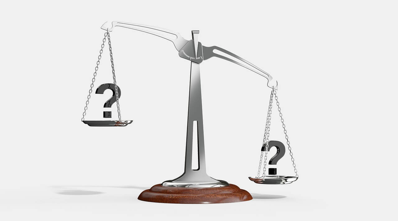 escala de plata de la Justicia más inclinada hacia un lado con signos de interrogación. 