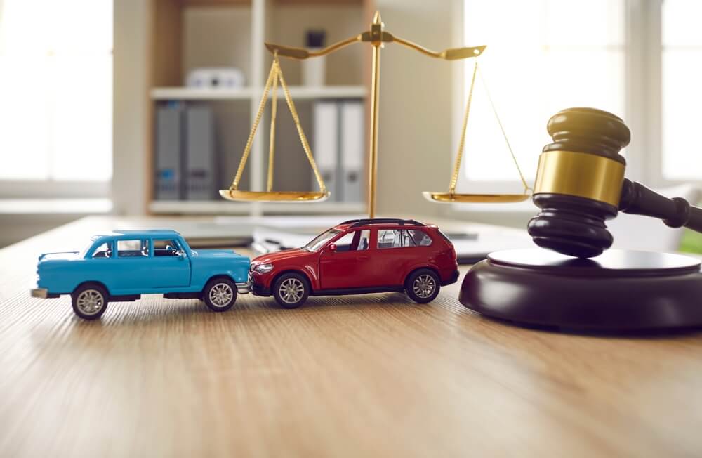 Coches de juguete en posición de accidente sobre la mesa de un abogado
