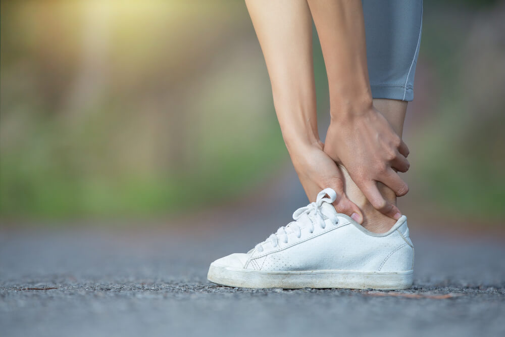 closeup of person holding her ankle in pain. 