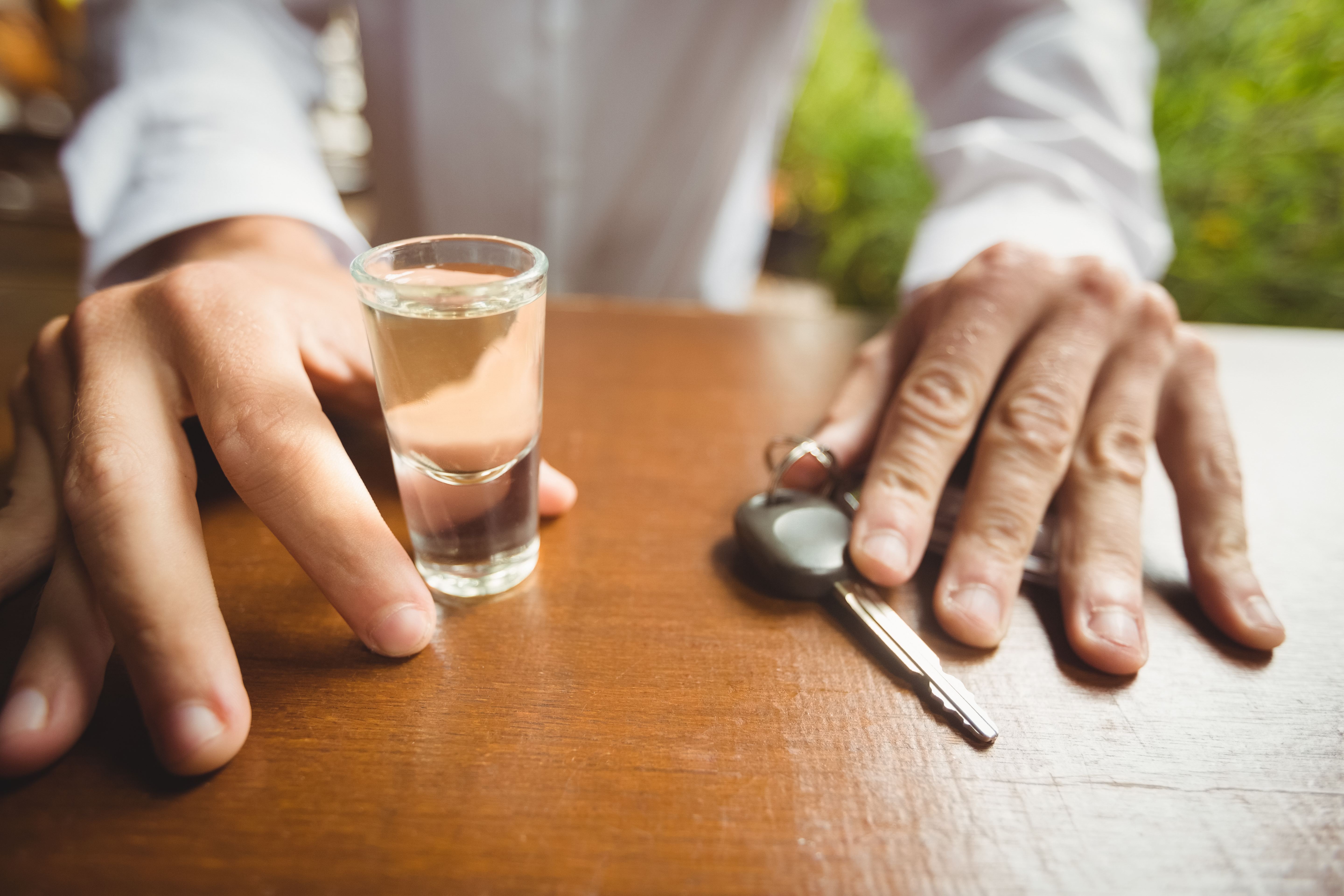 hombre con vaso de tequila chupito llave de coche barra de bar