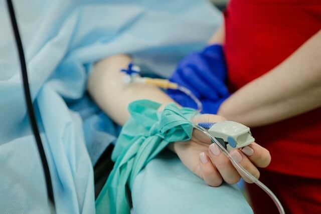 persona tumbada en una cama de hospital siendo atendida