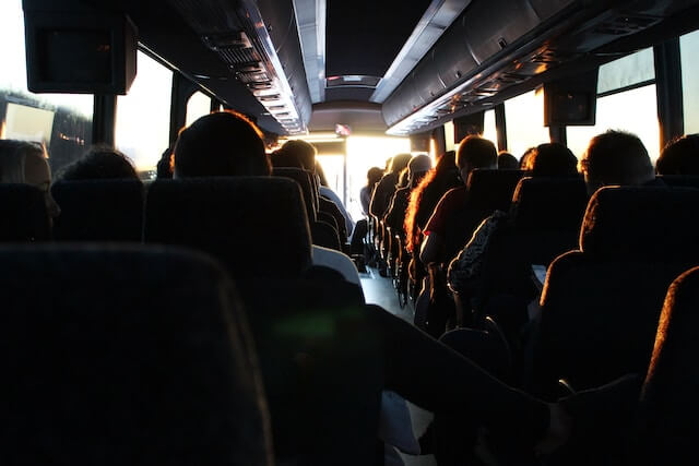 Foto del interior de un autobús con muchos pasajeros sentados. 
