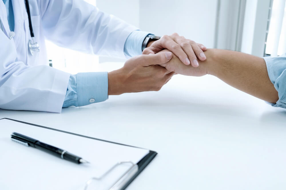 Médico cogiendo a un paciente de la mano con cuidado