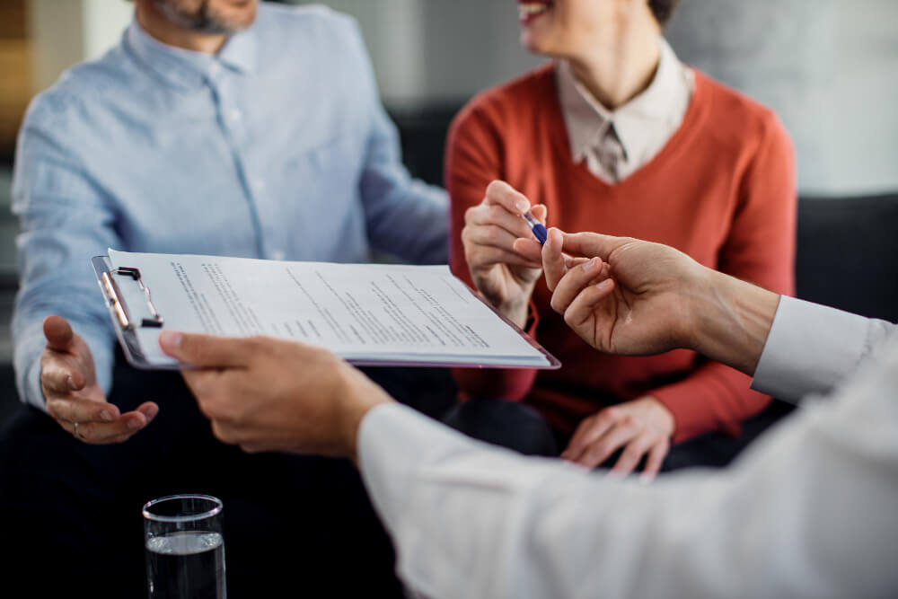 primer plano pareja irreconocible firmando contrato con asesor financiero