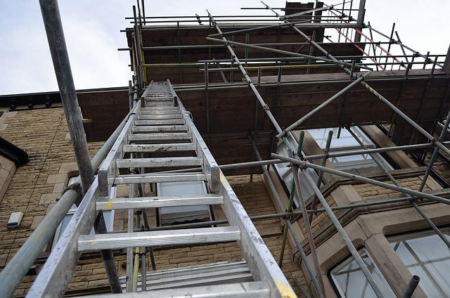 Escalera montada sobre un andamio en el lateral de un edificio. 
