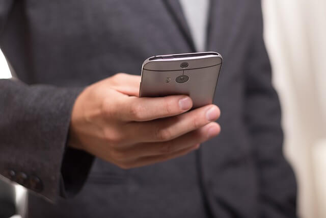 Hombre trajeado usando su teléfono para guardar información de contacto 