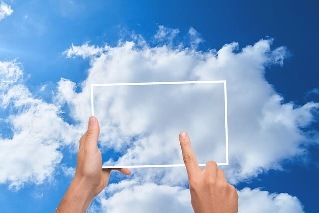 2 manos haciendo una foto a las nubes insinuando copia de seguridad en la nube. 