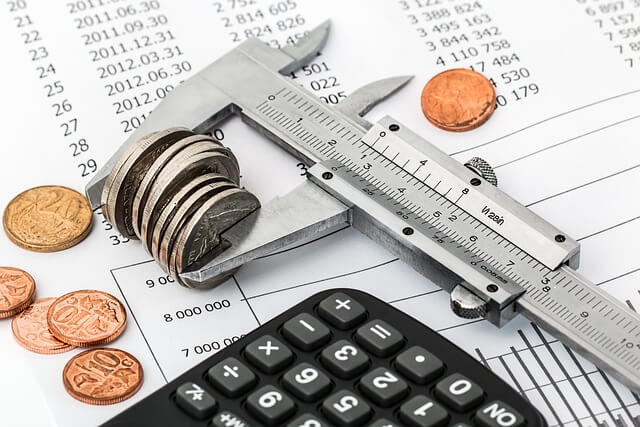 Regla de medir con monedas en el barro y una calculadora