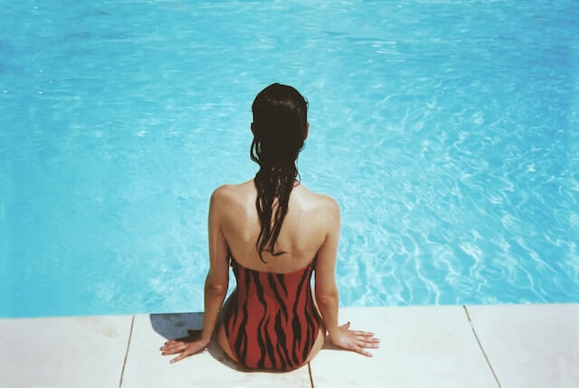 Mujer sentada en el borde de una piscina. 