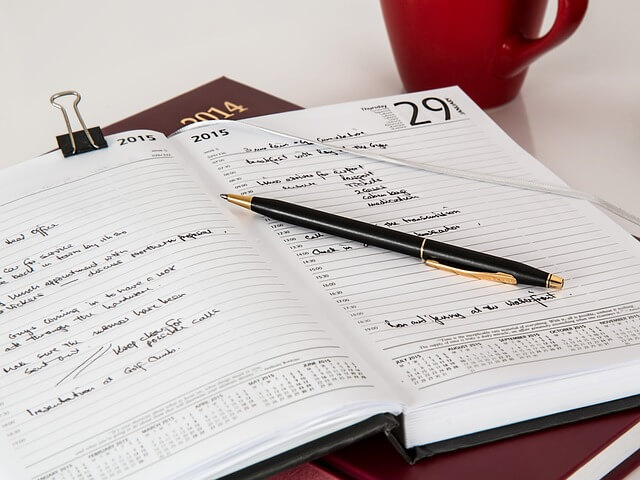 A calendarized book with dates and a pen on top. 