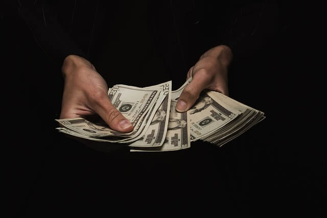 Hand counting dollars with a black background. 