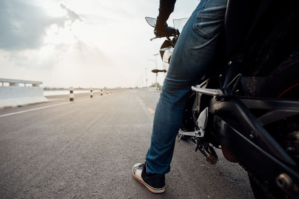 Ángulo lateral de motocicleta con hombre encima listo para despegar camino largo. 