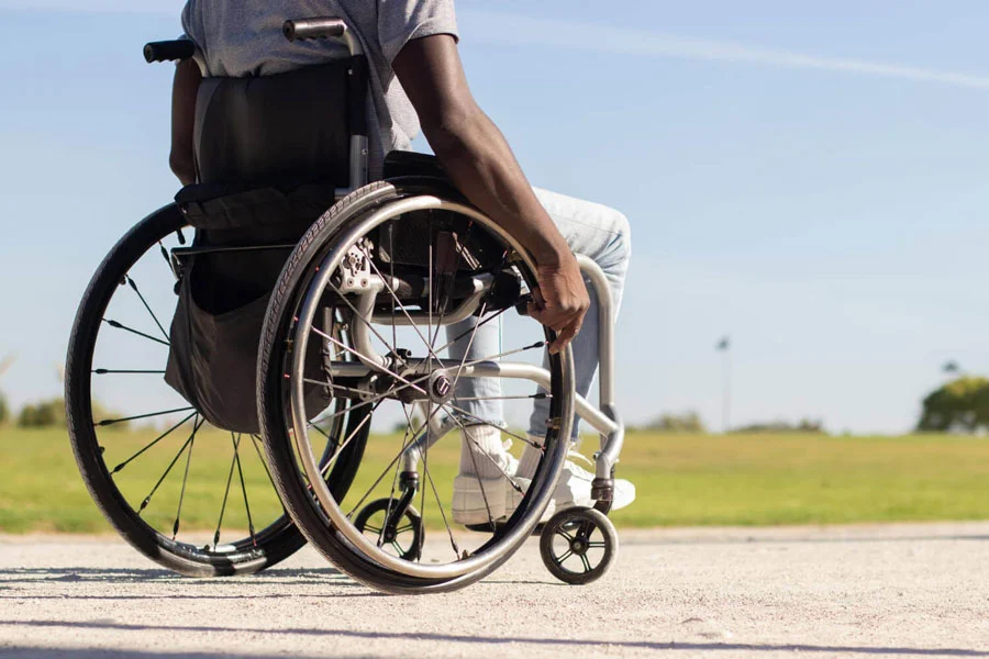 photo of paralyzed black man in wheelchair riding along park road