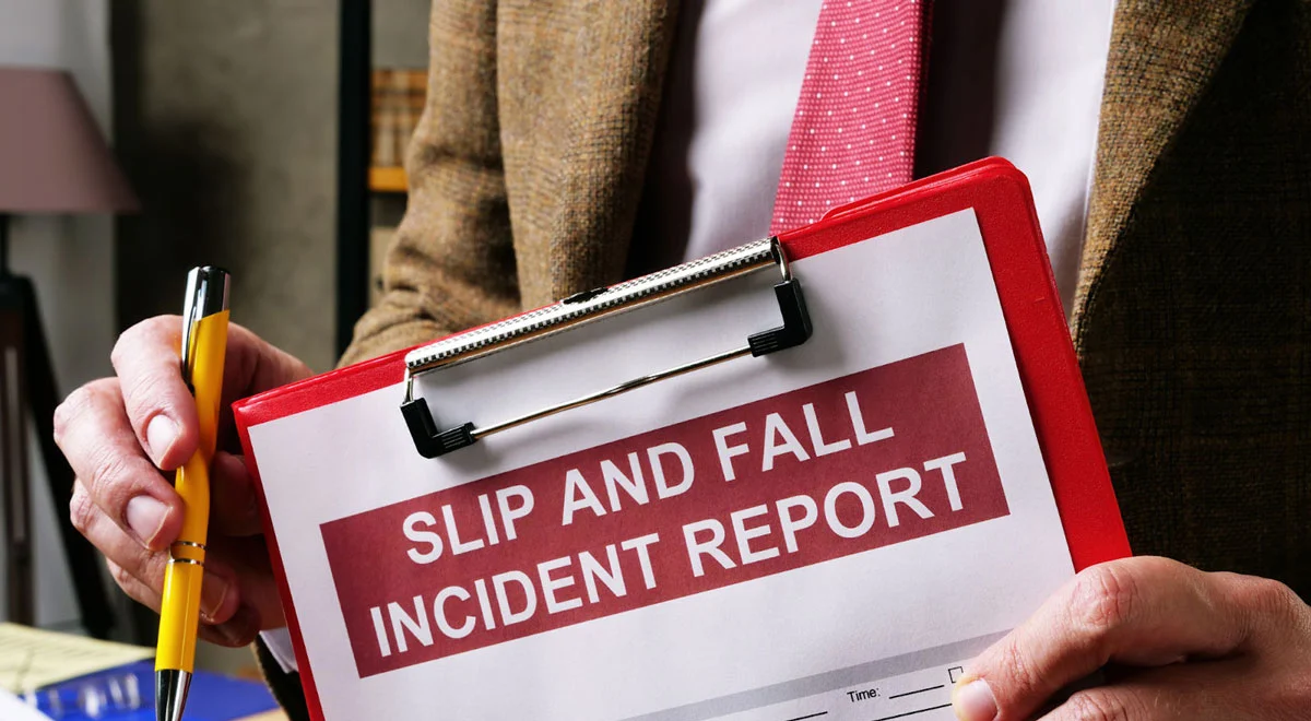 Close up of a man carrying a slip and fall incident report with a pen.