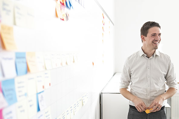 One person writes ideas and keywords with a marker on a transparent whiteboard