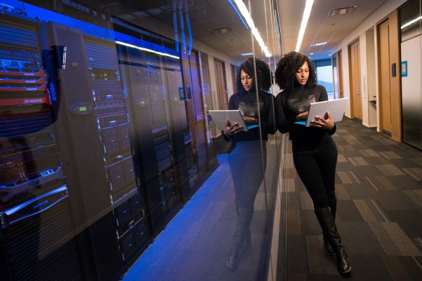 Woman leaning agaist a tack of servers in a server room