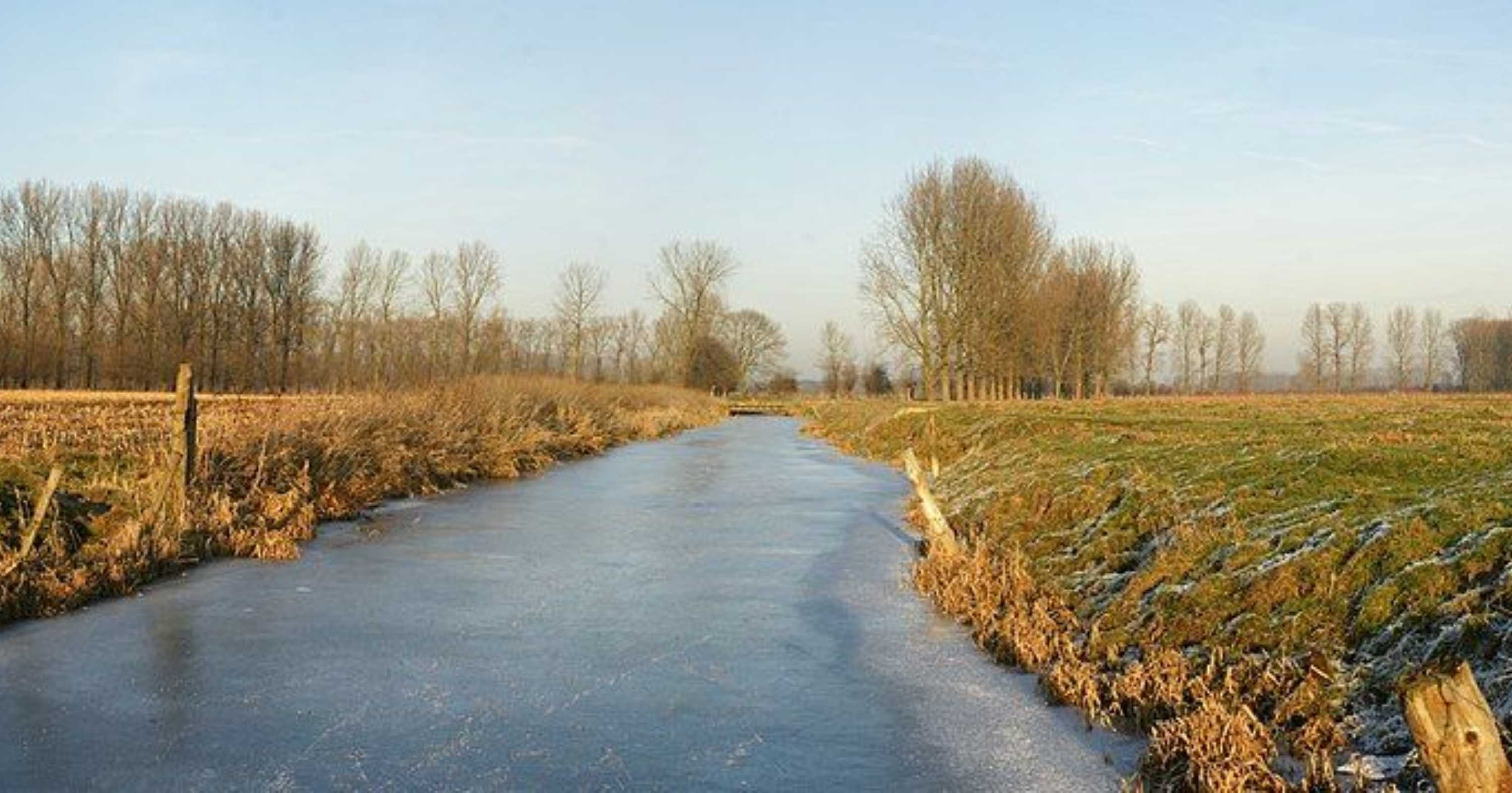 A frozen river running through a grassy landscape at Assebroekse Meersen, Belgium