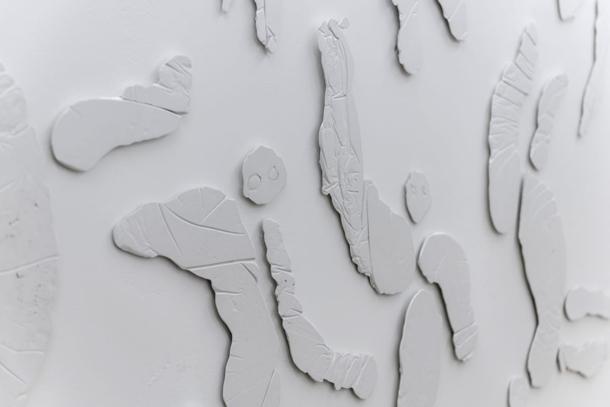 The image shows the image of a close up of an artwork, it looks like figures plastered on the wall
