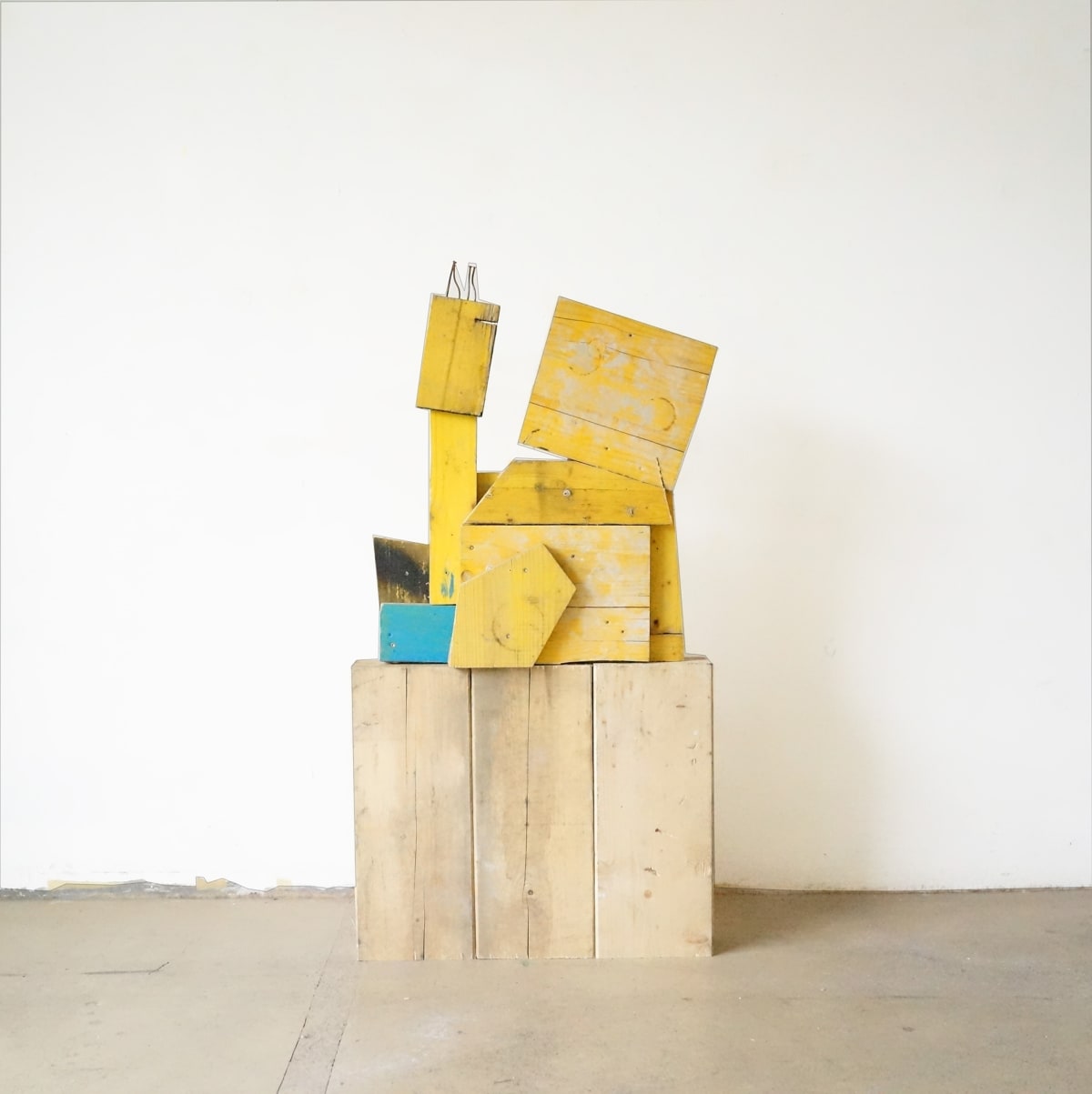 ernst koslitsch work shows a yellow and blue sculpture on blocks of unpainted wood
