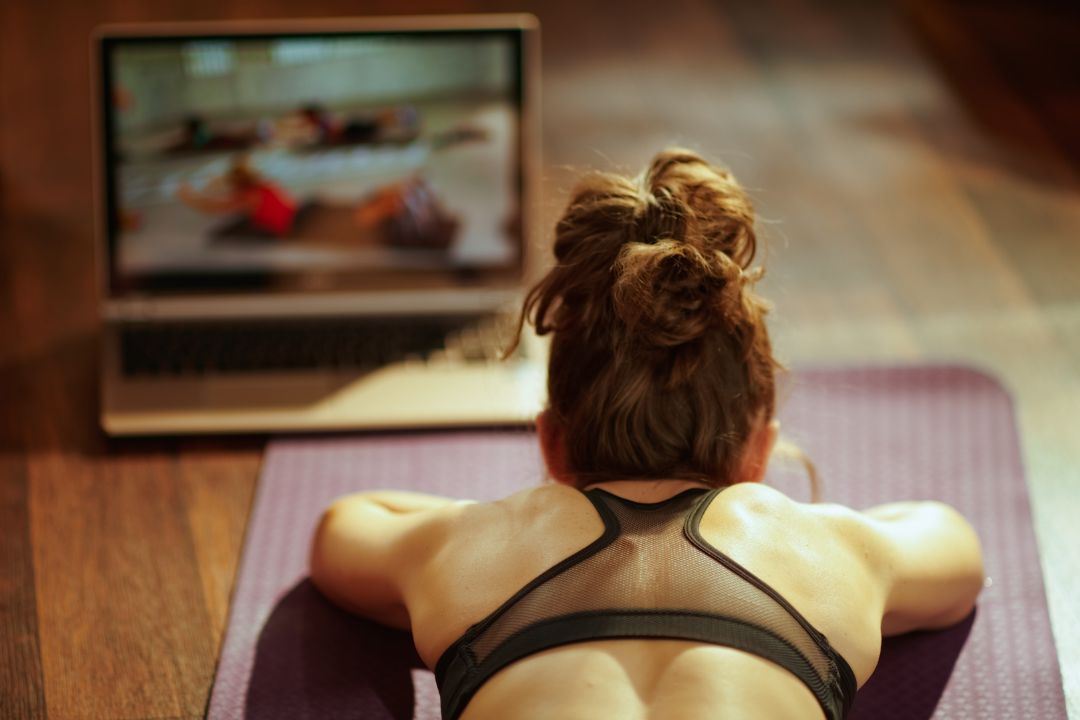 Women in the middle of a live-stream yoga session looking at her laptop