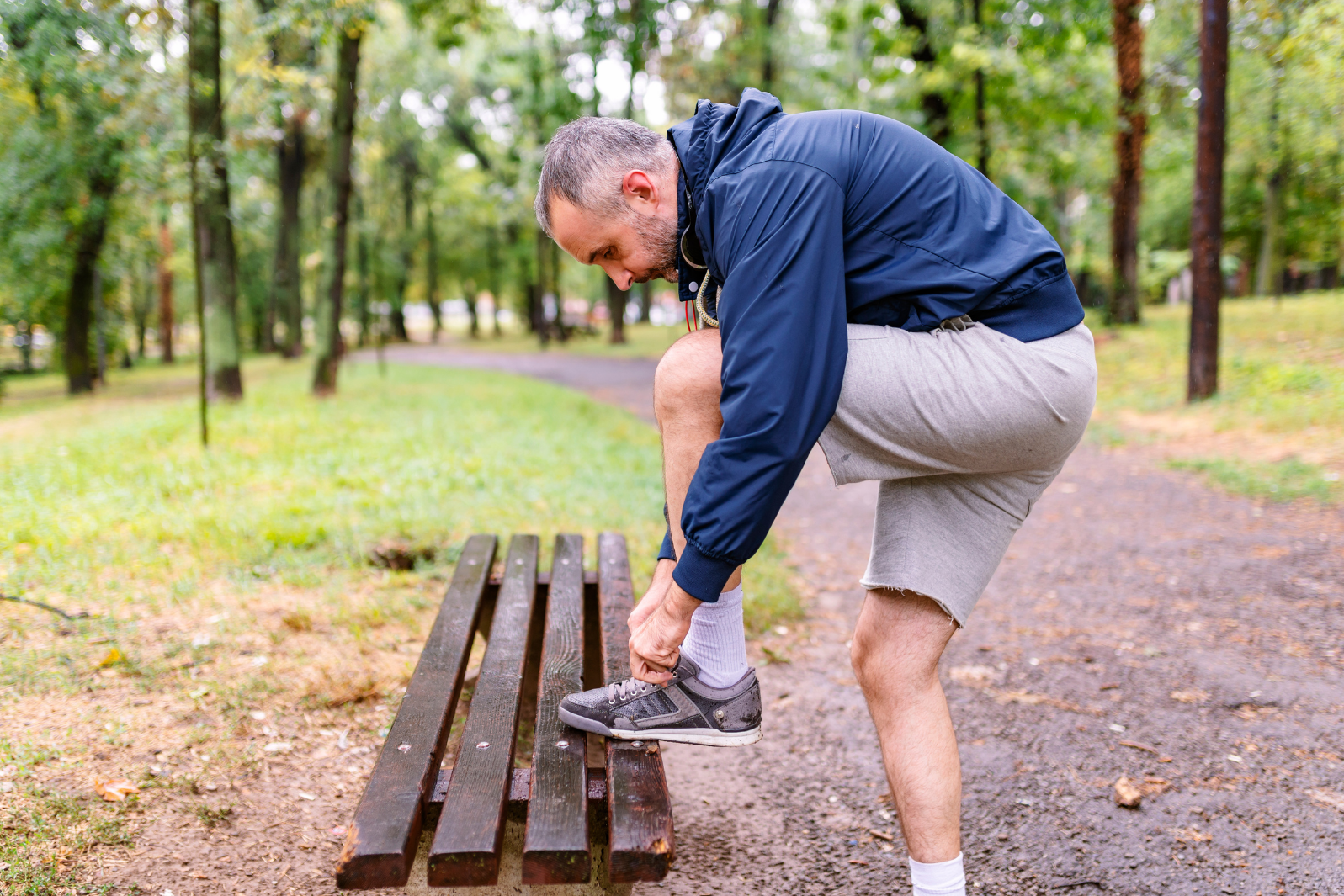 Man in his 40s tying up his laces for a run in the woods