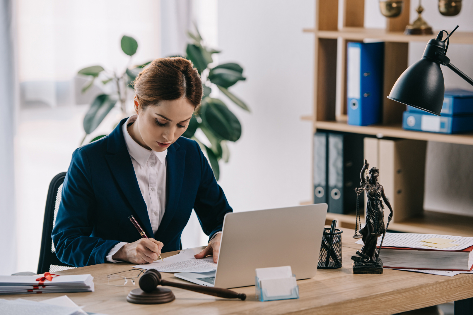 Well suited female lawyer taking down notes at her desk