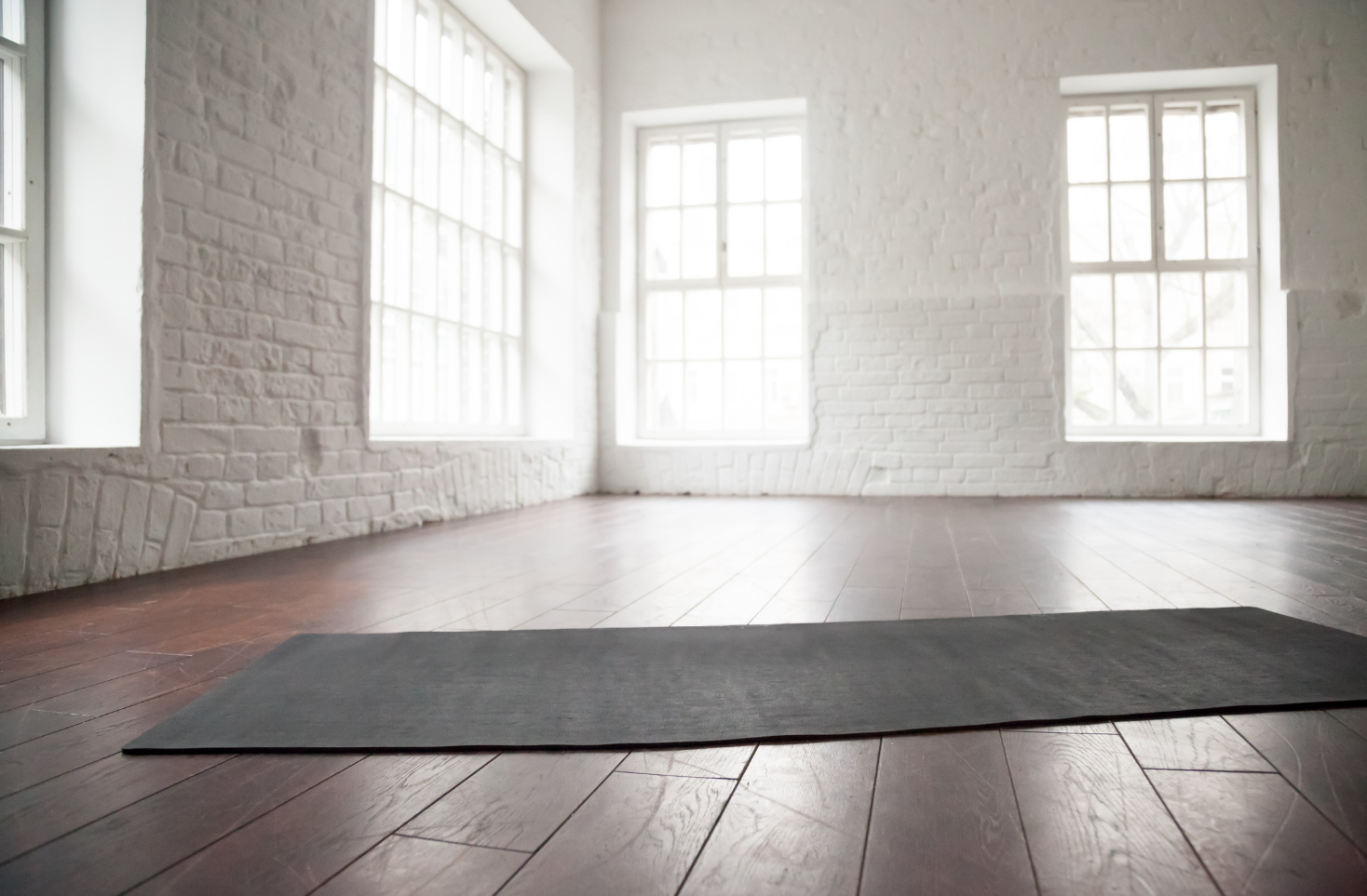Empty yoga studio with a grey yoga mat inside.