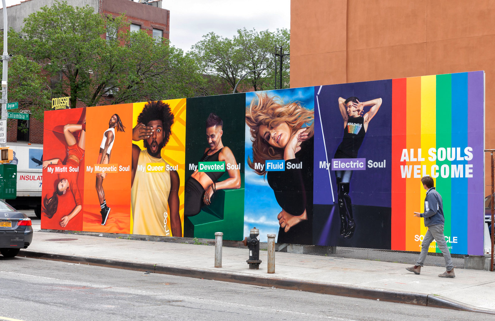 A man walking past a SoulCyle banner on the street.