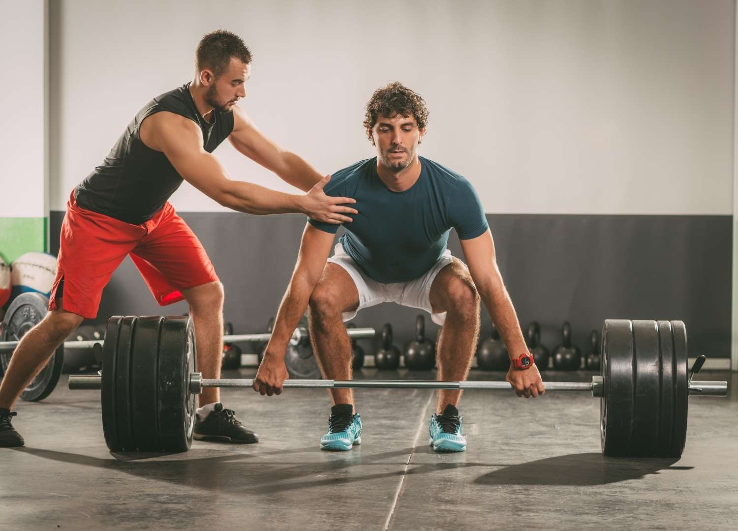 An instructor assisting a man in weight lifting