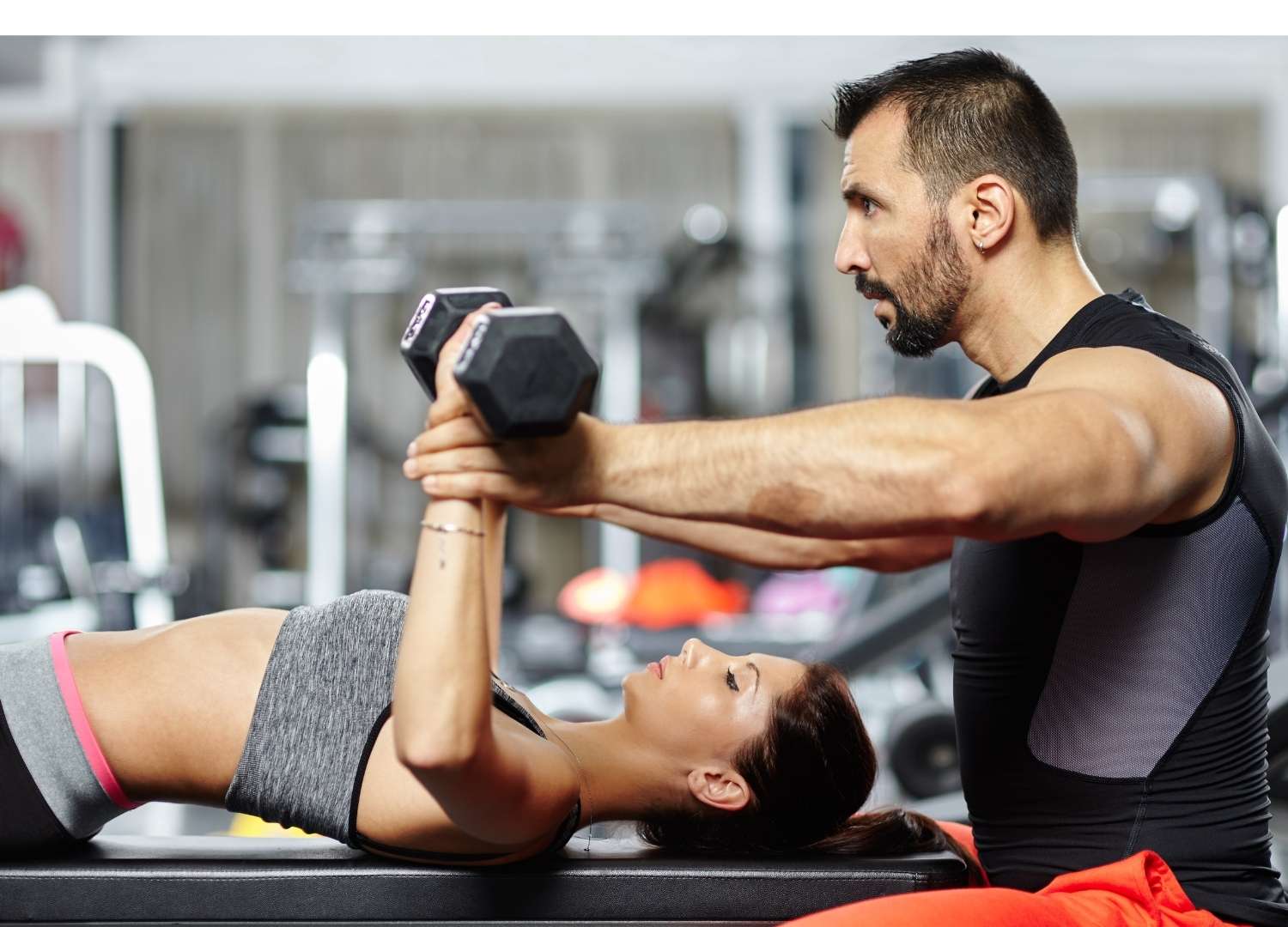 Instructor helping out a woman in weight lifting