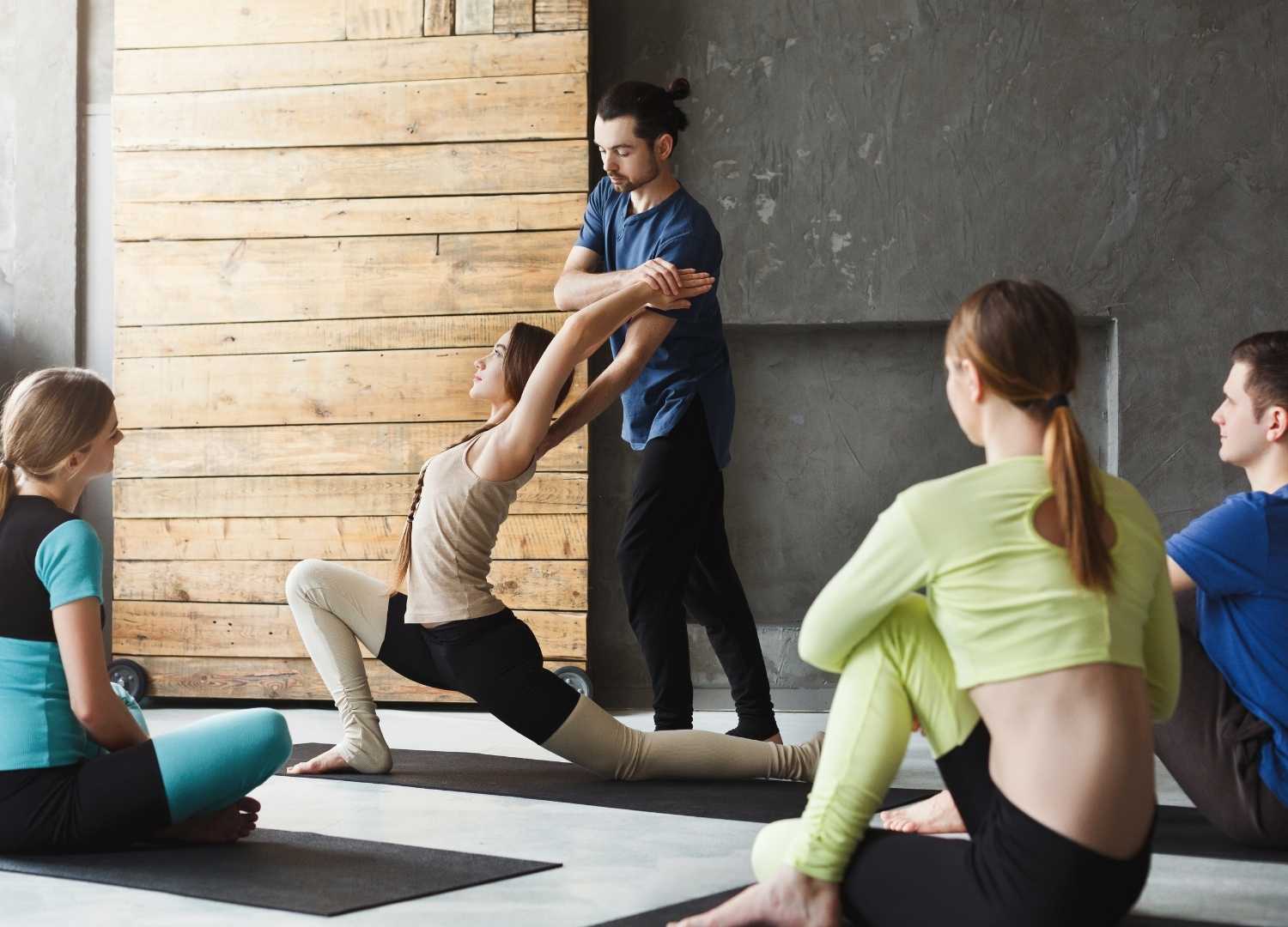 An ongoing yoga class with an instructor teaching yoga pose to a student