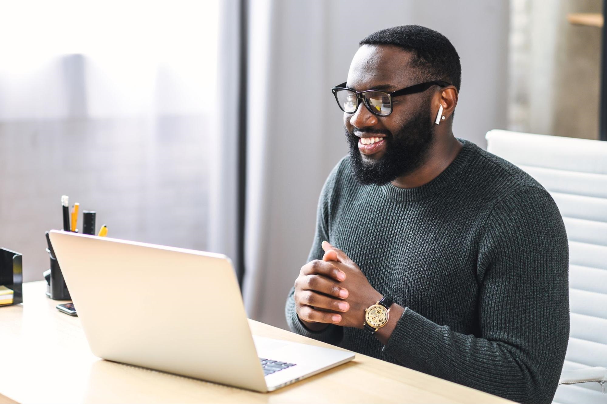 customer retention software: Smiling man looking at his laptop