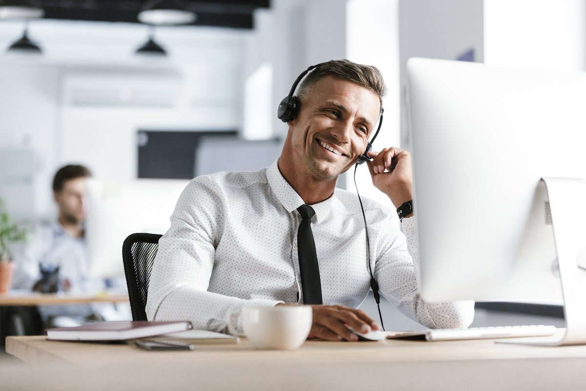 lead response: Smiling man wearing a headset while looking at his monitor