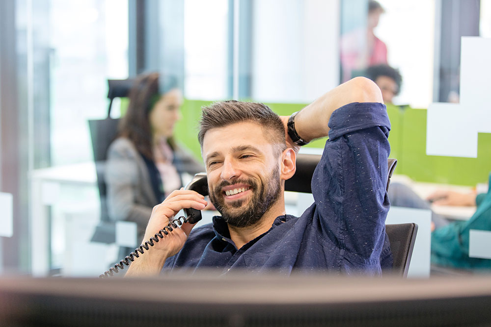 Man smiling using VoIP based office phone system