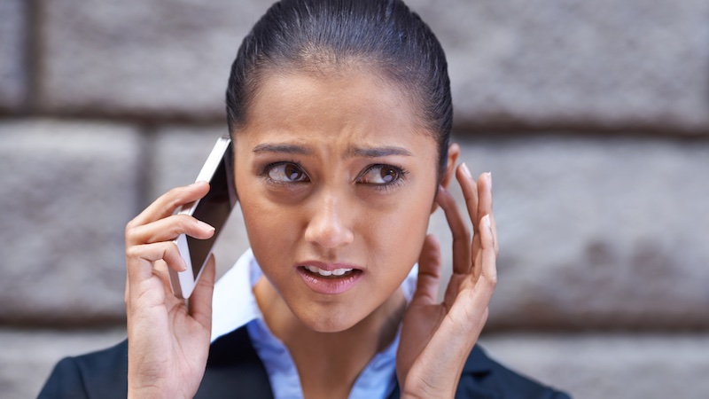 A woman struggling to hear a voicemail message