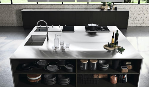 Cucina moderna scura con isola centrale e piano di lavoro in acciaio inox con lavello e piano cottura