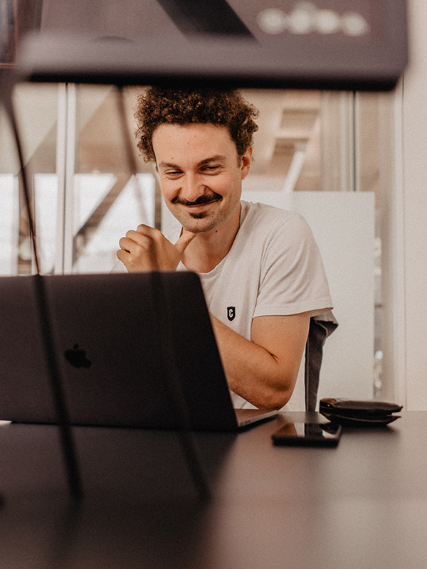 A person smiling, sitting in front of a laptop