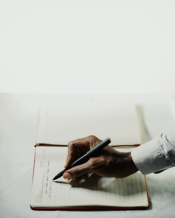 Une main tient un stylo et écrit sur un cahier